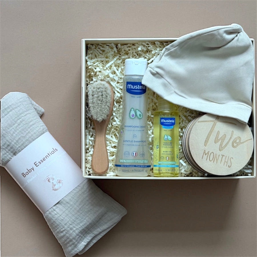 A newborn baby gift box with Mustela care products, a blanket and milestone cards